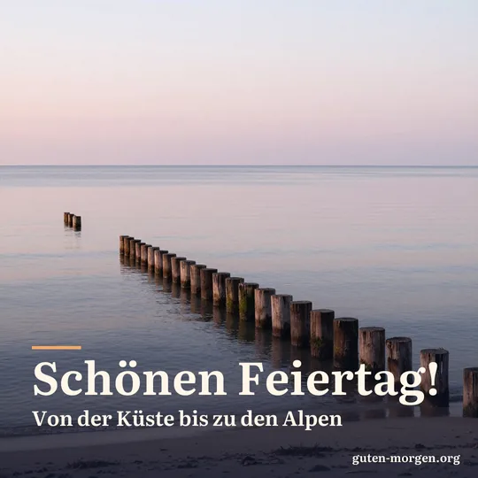 Ruhiger Ostseestrand bei Sonnenaufgang im Herbst, alte Holzbuhnen ragen ins Wasser, zartes rosa Licht; Schrift: „Schönen Feiertag! Von der Küste bis zu den Alpen“