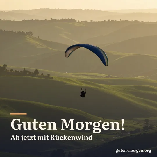 Silhouette eines Gleitschirmfliegers über sanften grünen Hügeln im goldenen Morgenlicht; Schrift: „Guten Morgen! Ab jetzt mit Rückenwind“