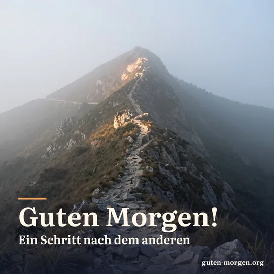 Schmaler Bergpfad, der sich durch Morgennebel nach oben windet, oben trifft das erste Sonnenlicht den Felsgrat; Schrift: „Guten Morgen! Ein Schritt nach dem anderen“