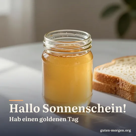 Honigglas auf dem Frühstückstisch, die Morgensonne scheint golden hindurch, daneben eine Scheibe Brot; Schrift: „Hallo Sonnenschein! Hab einen goldenen Tag“