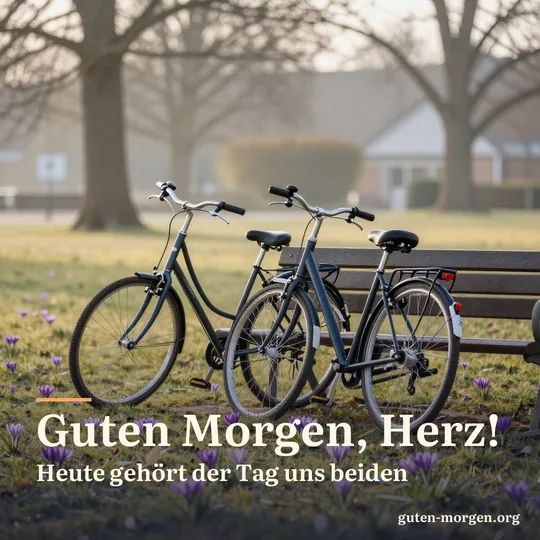 Zwei Fahrräder lehnen aneinander neben einer Parkbank, Krokusse im Gras, tiefe Morgensonne; Schrift: „Guten Morgen, Herz! Heute gehört der Tag uns beiden“